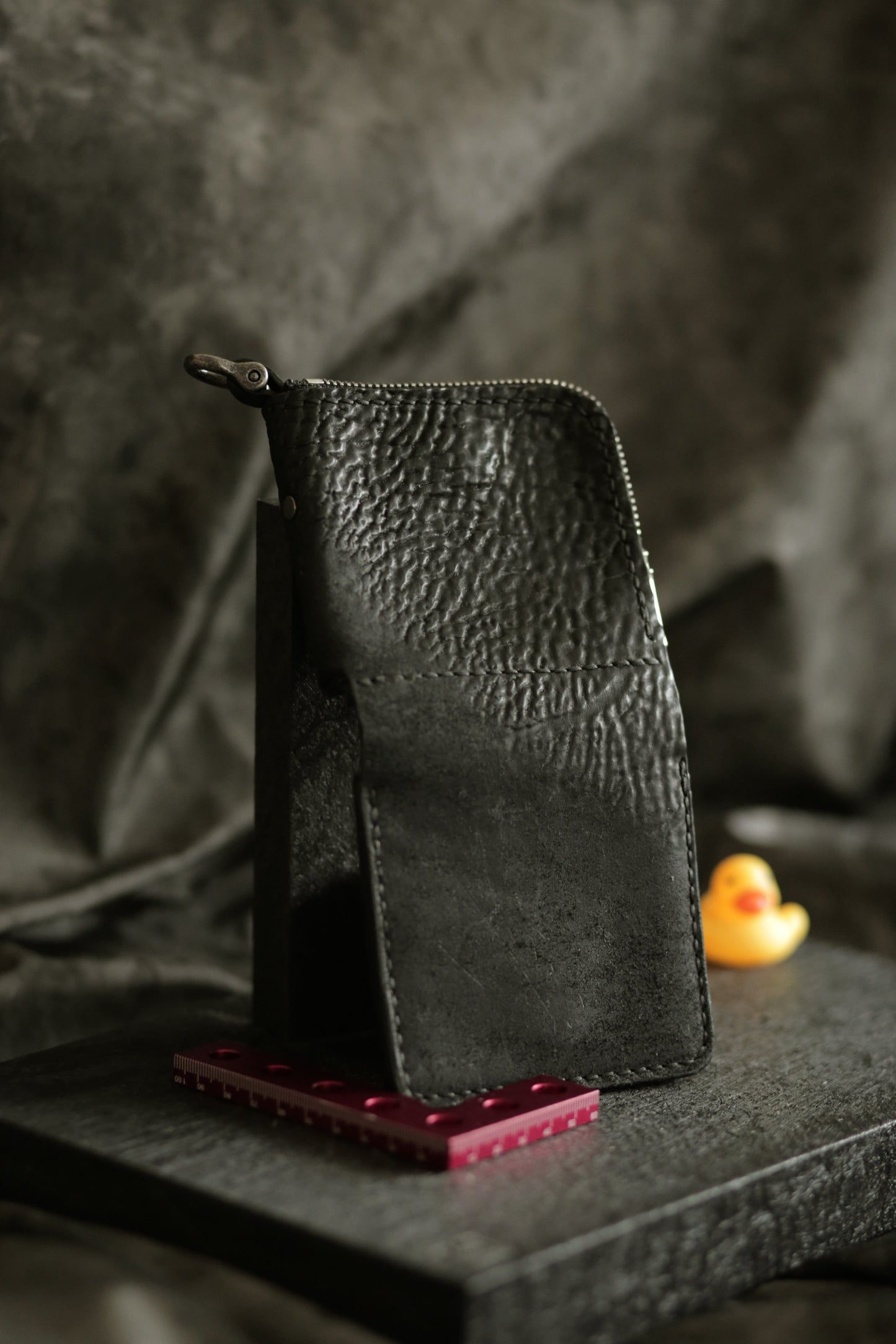 Boddin #007 handmade black leather wallet with textured finish, zipper pouch, and snap button detail on dark background.