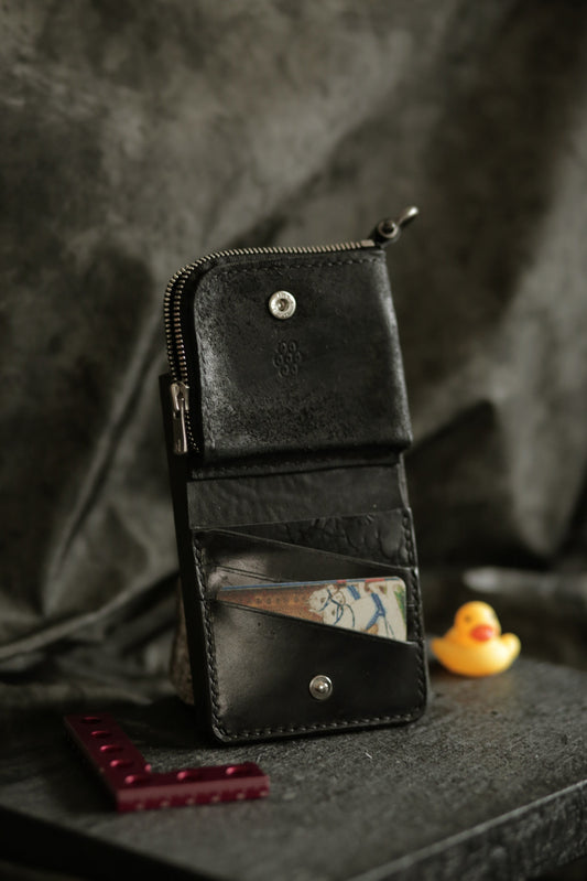Boddin #007 handmade black leather compact wallet with zipper pouch, card slots, and snap buttons on textured background.