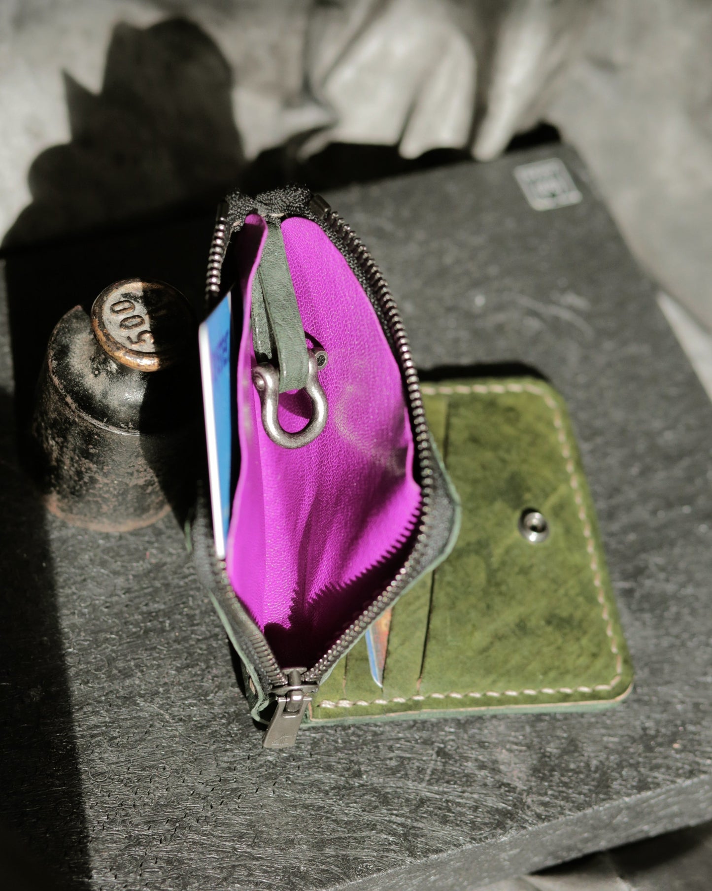 Boddin #008 (new prototype) handmade green leather wallet with purple zip pouch and brass shackle detail on black surface.