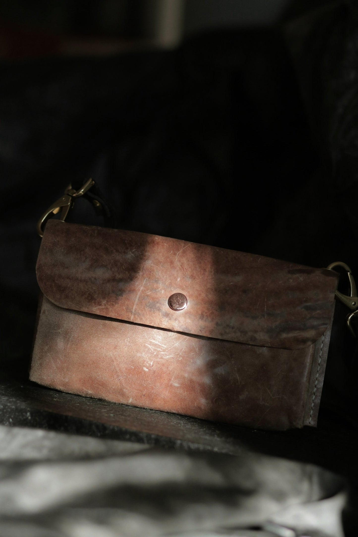 Köpenicker #002 prototype natural skin leather clutch with shoulder strap and copper button in soft light.