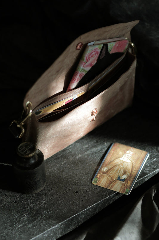 Köpenicker #002 prototype clutch in natural skin, open with visible card slots and brass hardware on dark surface.