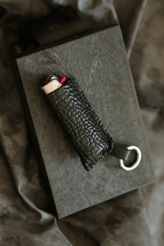 Lighter with a black horse culatta leather case featuring a metal keyring.