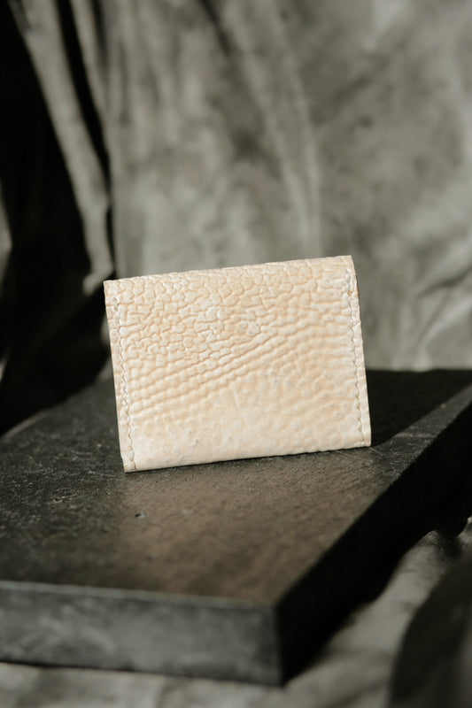 Hermann minimal snap wallet in dirty white reverse horse culatta leather with textured finish on dark surface.