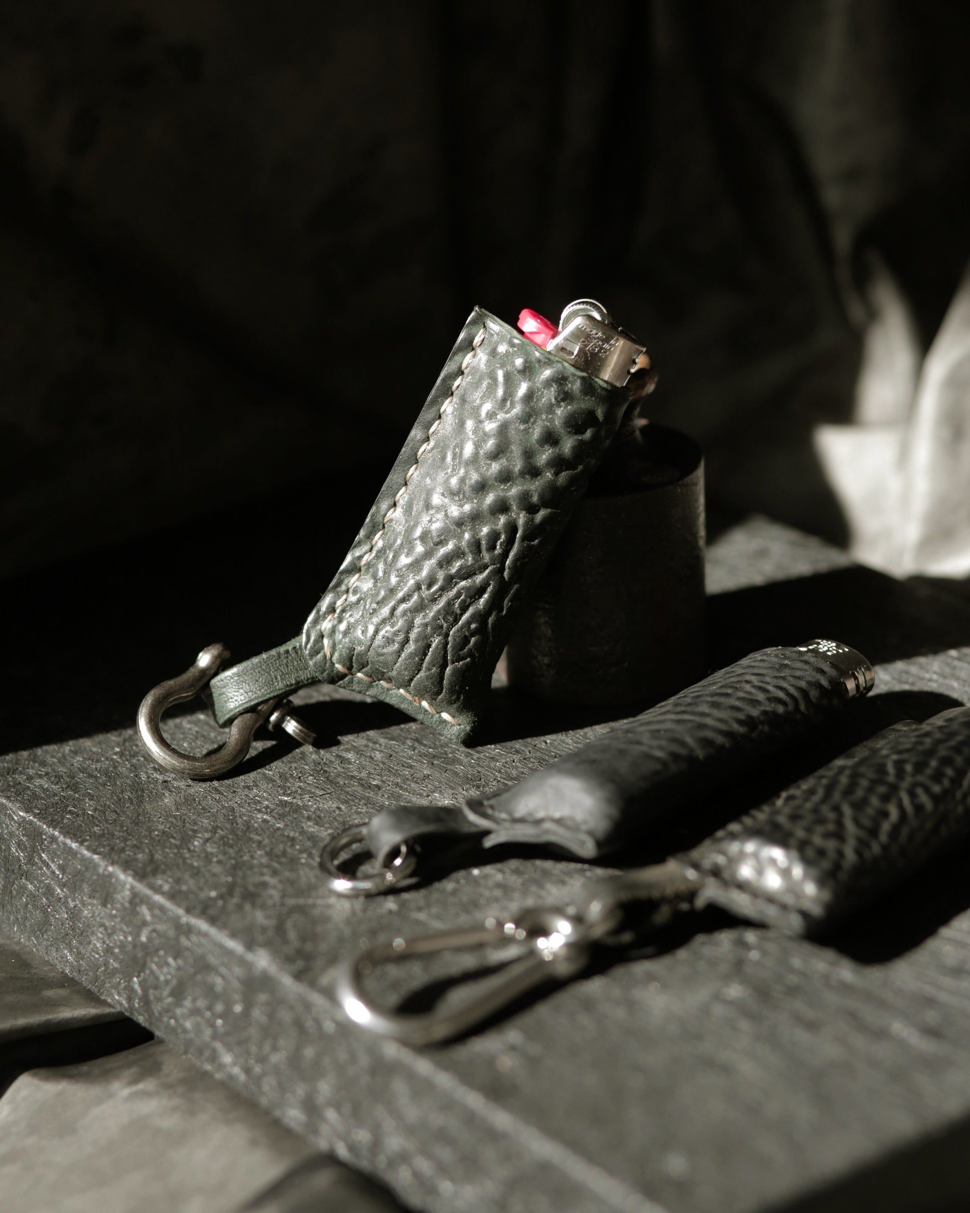 Lighter with horse culatta leather case in dark green and polished black, with metal hardware clips.