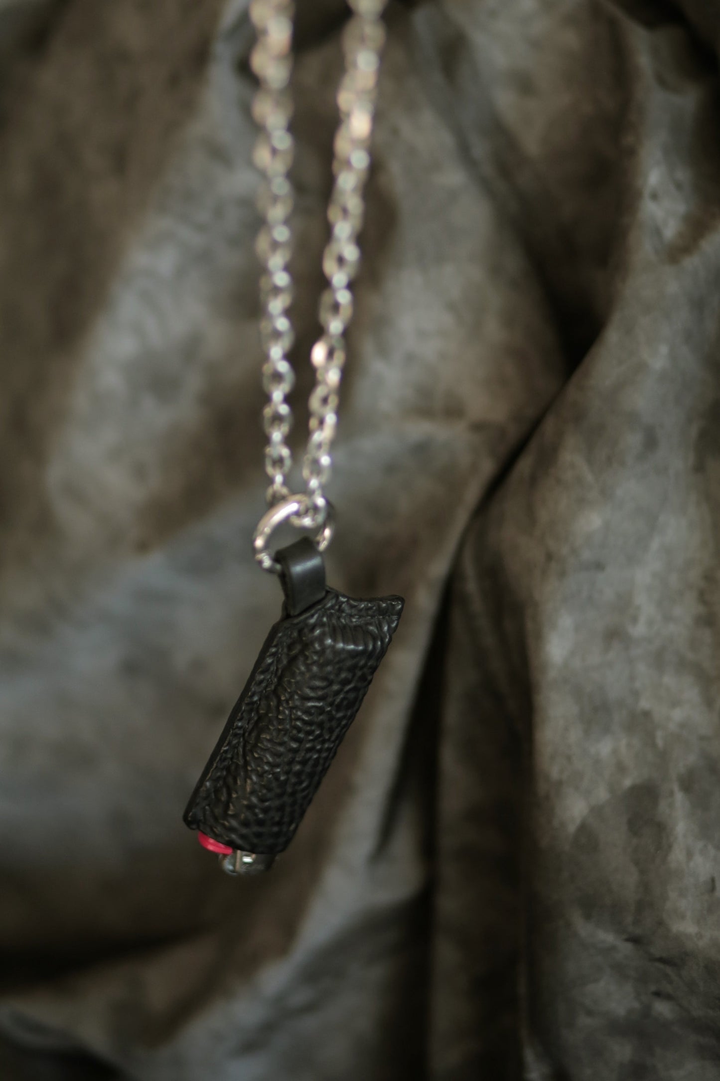 Lighter with a black horse culatta case hanging on a silver chain.