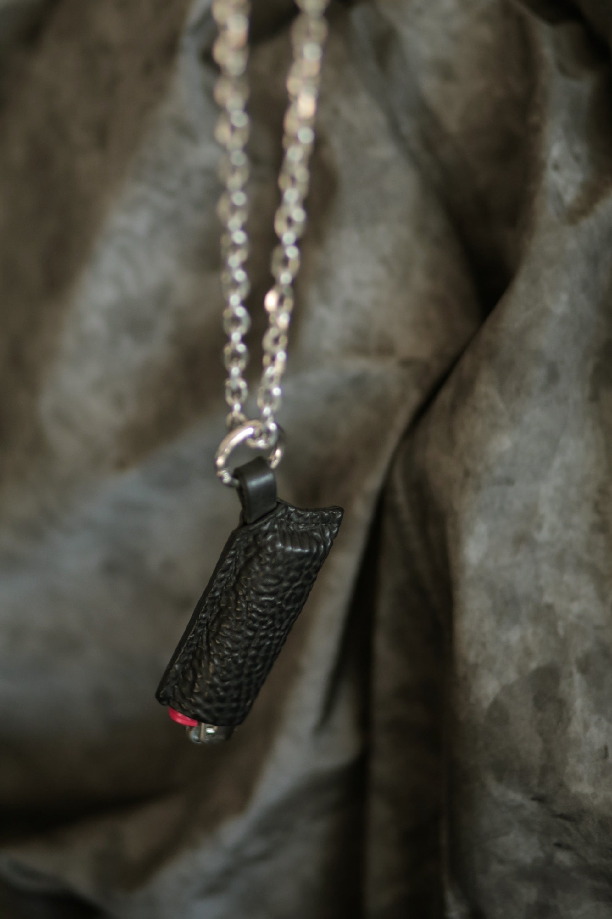 Lighter with a black horse culatta case hanging on a silver chain.