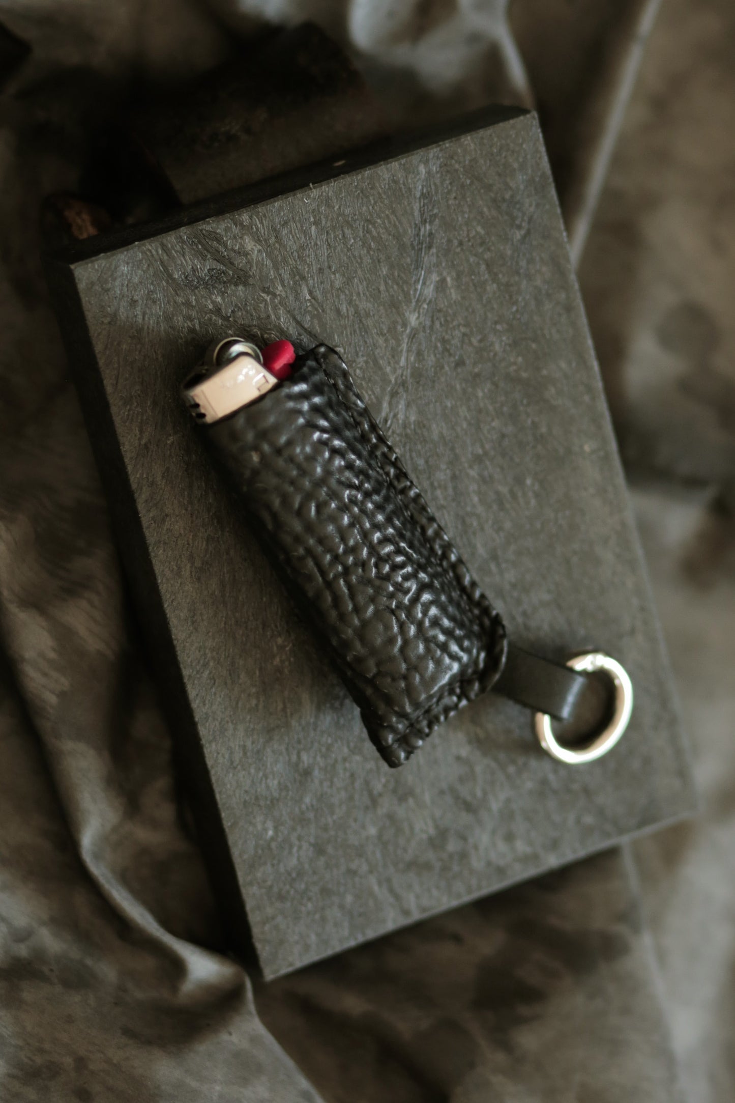 Lighter with a black horse culatta leather case featuring a metal keyring.